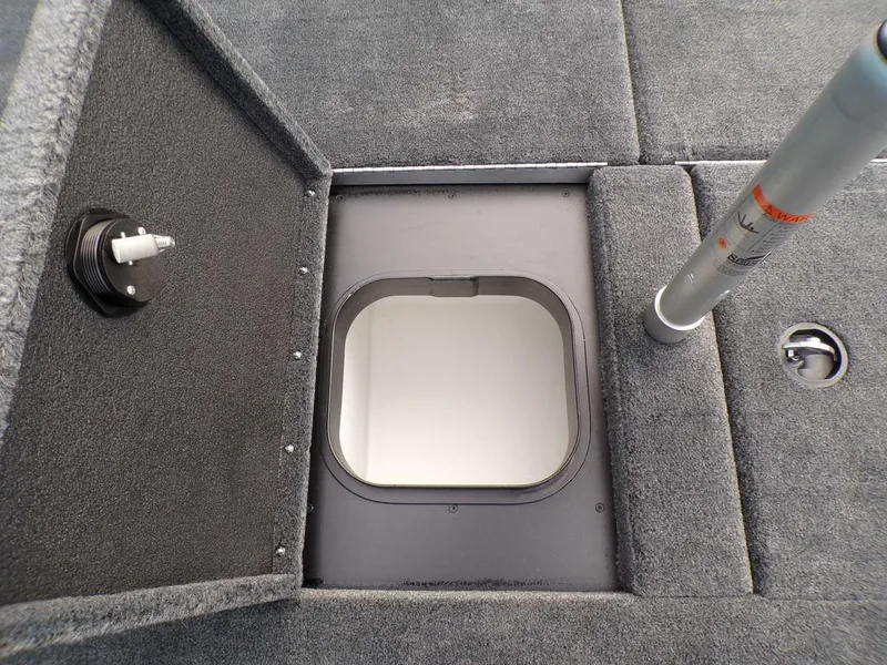 Slide: The Image of 2025 Skeeter ZXR20 boat storage compartment with open hatch and carpeted interior. - 21