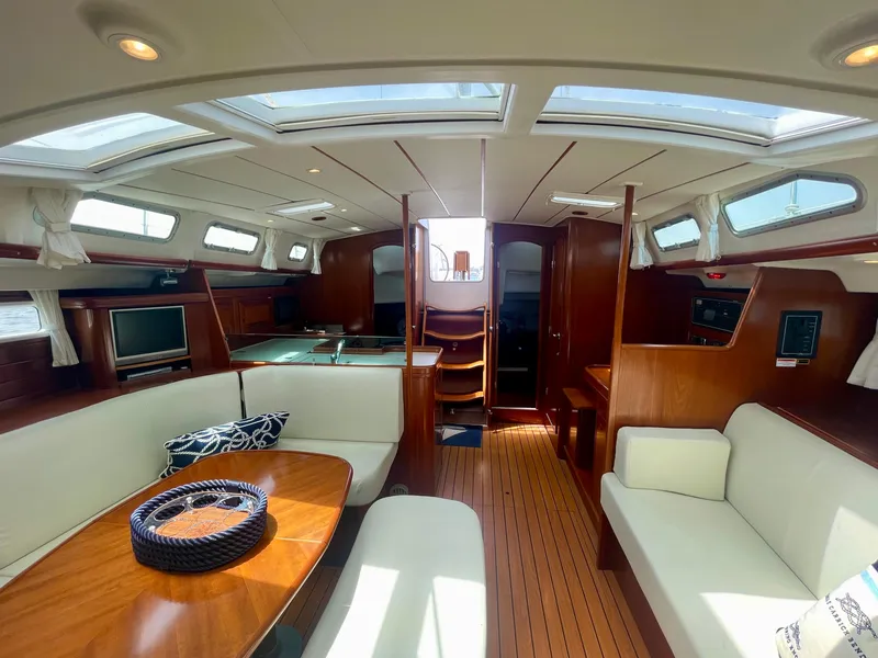Slide: The Image of Interior of 2004 Beneteau Oceanis Clipper 473 yacht, featuring elegant wood finishes and spacious seating. - 11