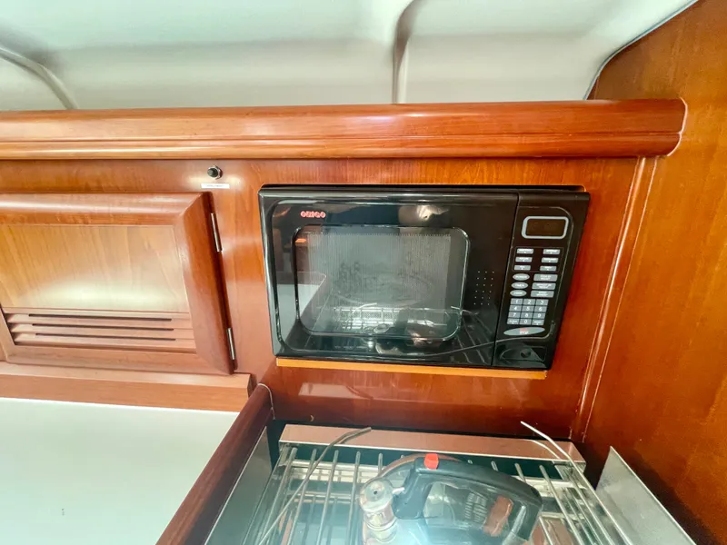 Slide: The Image of Microwave in 2004 Beneteau Oceanis Clipper 473 yacht kitchen with wooden cabinetry. - 22