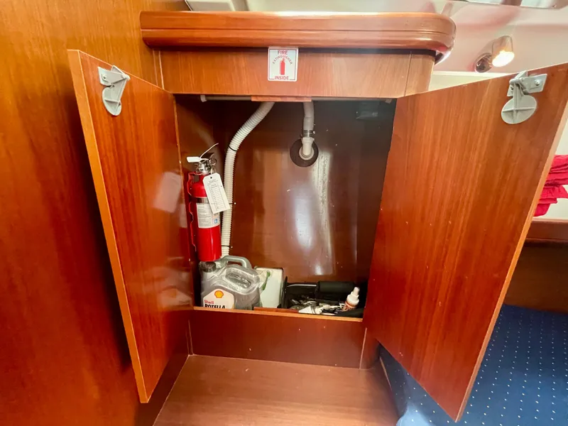 Slide: The Image of Open cabinet on 2004 Beneteau Oceanis Clipper 473 yacht, showing fire extinguisher and storage. - 28