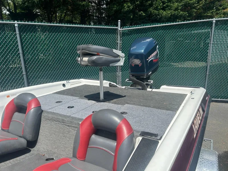 Slide: The Image of 2000 Javelin 20 Renegade boat with seating and outboard motor, parked by a fence. - 4