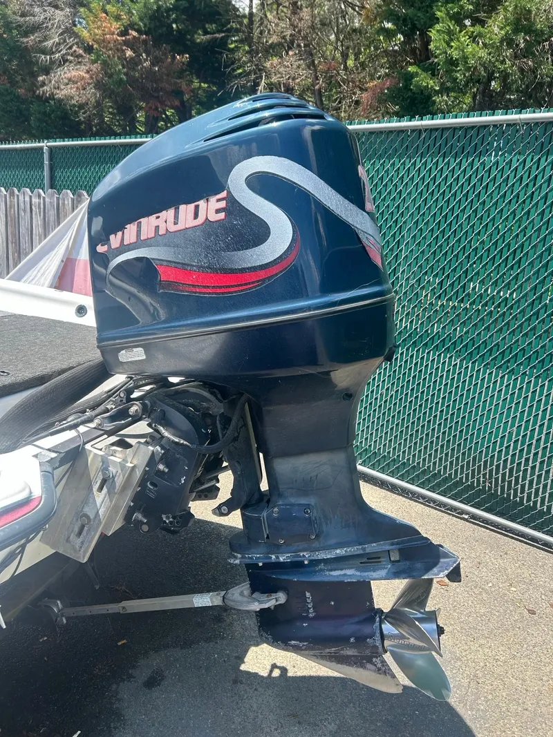 Slide: The Image of 2000 Javelin 20 Renegade boat with Evinrude outboard motor, parked near a green fence. - 5