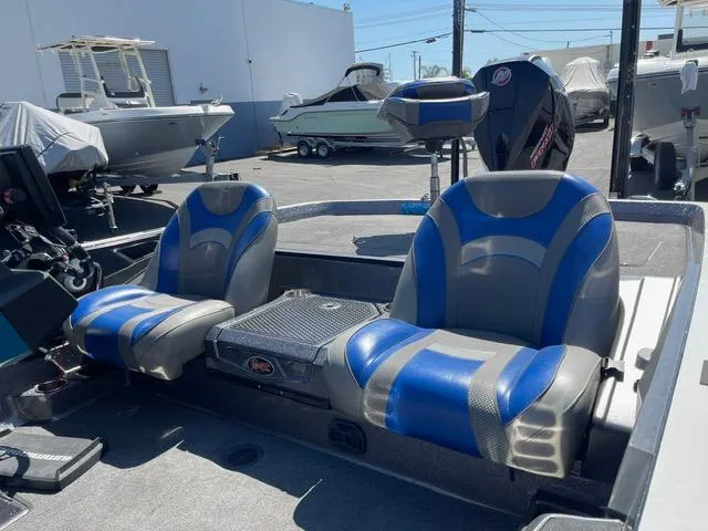 Slide: The Image of 2018 Ranger Z521L boat interior with blue and gray seats in a marina setting. - 8