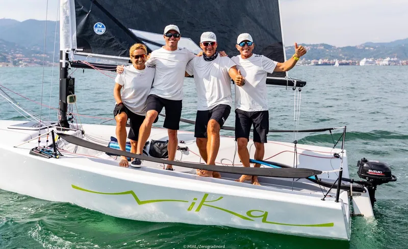 Slide: The Image of Four people on a 2016 Melges 20 sailboat named "Vika" on the water. - 7
