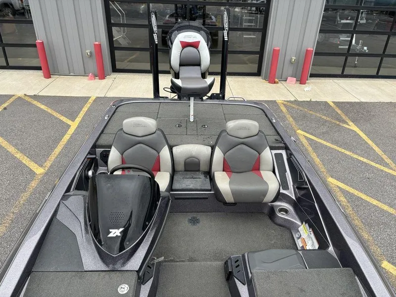 Slide: The Image of 2017 Skeeter ZX250 boat interior with dual seats and steering console, parked near a building. - 16