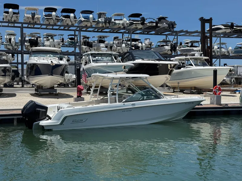 Slide: The Image of 2018 Boston Whaler 270 Vantage docked at marina with multiple boats in background. - 2