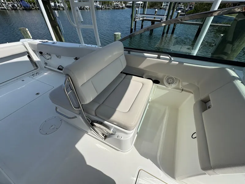 Slide: The Image of 2018 Boston Whaler 270 Vantage boat interior with cushioned seating and waterfront view. - 24