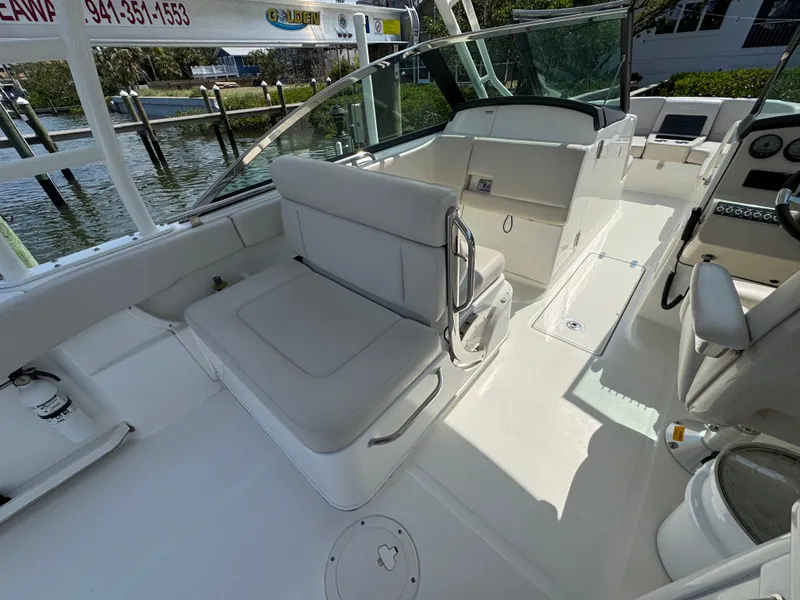 Slide: The Image of 2018 Boston Whaler 270 Vantage boat interior with seating and helm, docked by the water. - 25
