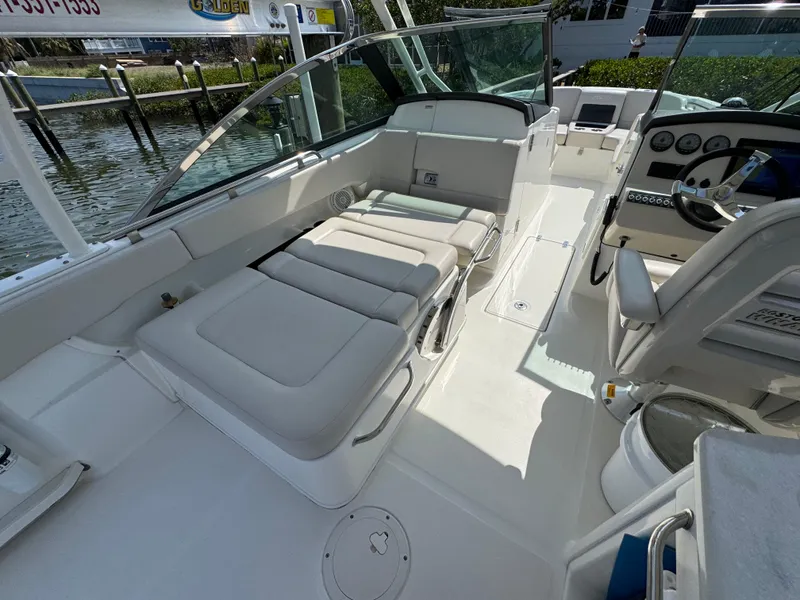 Slide: The Image of 2018 Boston Whaler 270 Vantage boat interior with seating and helm, docked by the water. - 26