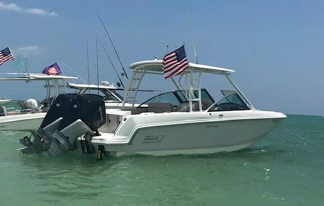 Slide: The Image of 2018 Boston Whaler 270 Vantage boat anchored in clear blue water with American flag. - 3
