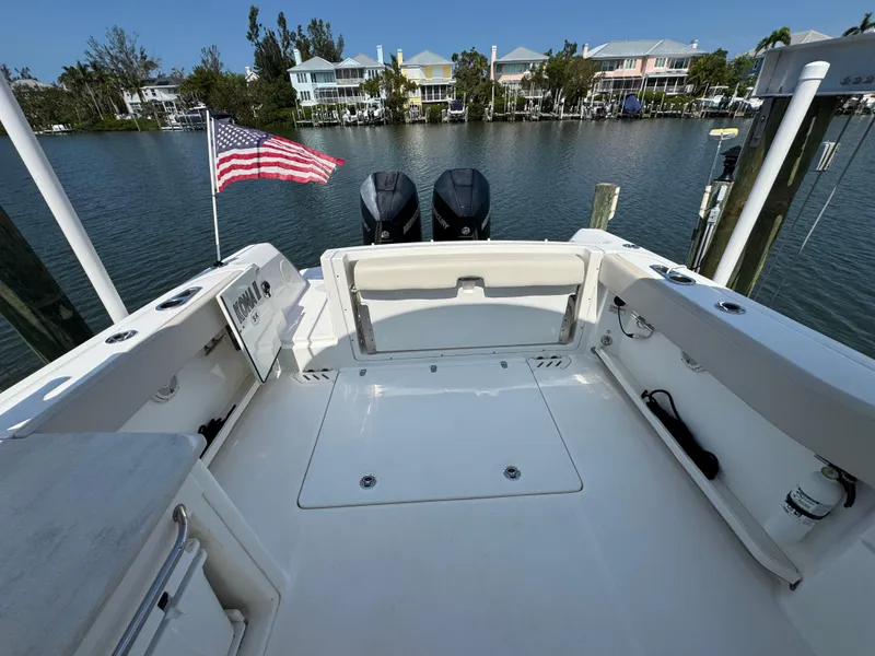 Slide: The Image of 2018 Boston Whaler 270 Vantage boat with American flag, docked by waterfront homes. - 30