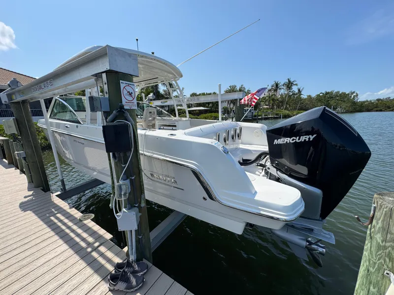 Slide: The Image of 2018 Boston Whaler 270 Vantage boat docked, featuring a Mercury engine, under clear blue skies. - 6