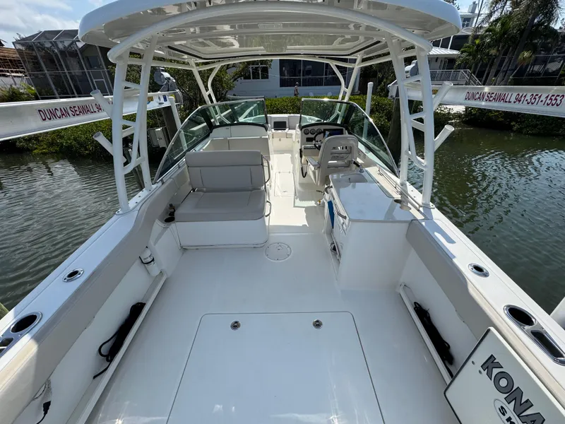 Slide: The Image of 2018 Boston Whaler 270 Vantage boat interior with seating and helm, docked by water. - 8