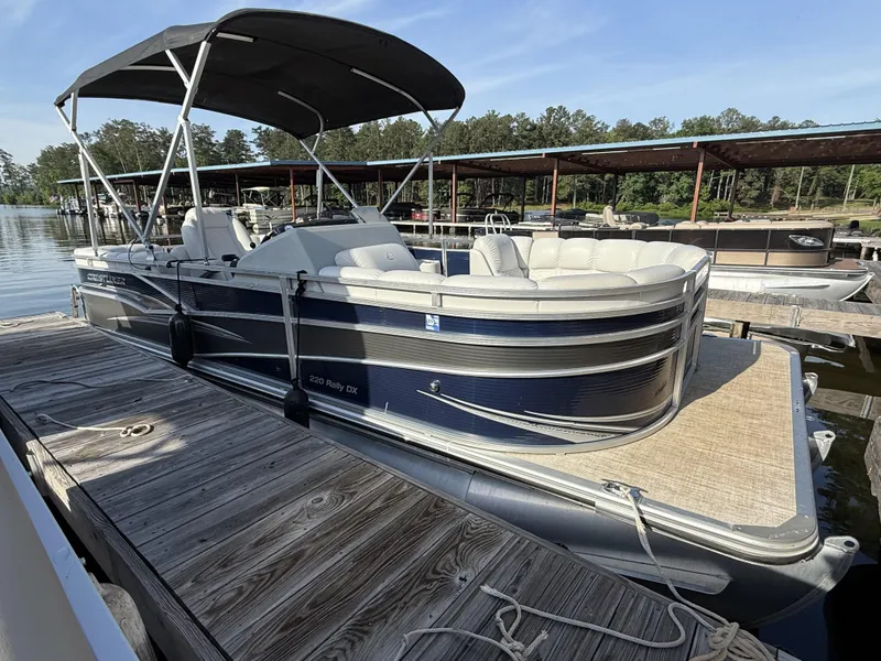 Slide: The Image of 2019 Crestliner 220 Rally DX pontoon boat docked, featuring a center walk-through design. - 8