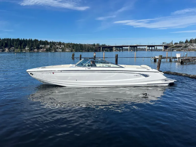 Slide: The Image of 2017 Cobalt A28 boat on a serene lake with a bridge and forested background. - 2