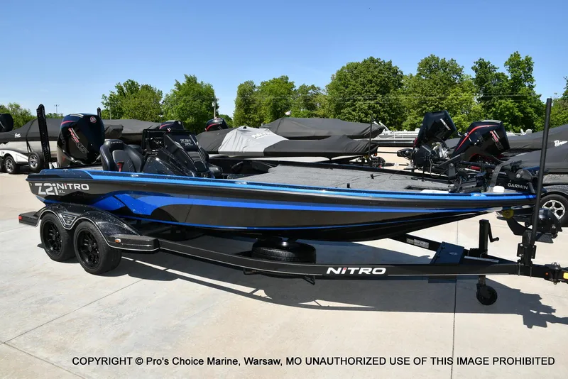 Slide: The Image of 2024 Nitro Z21 XL Pro Pack boat on trailer, parked outdoors, with trees in the background. - 67