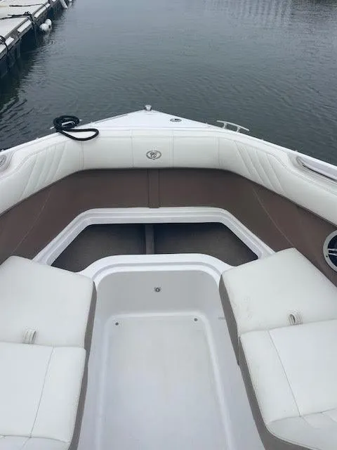 Slide: The Image of 2011 Cobalt 222 boat interior with white seating and brown accents at a dock. - 15