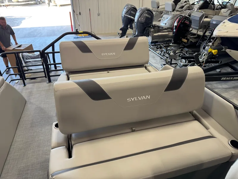Slide: The Image of 2025 Sylvan L 5 boat seats in showroom with engines in background. - 17