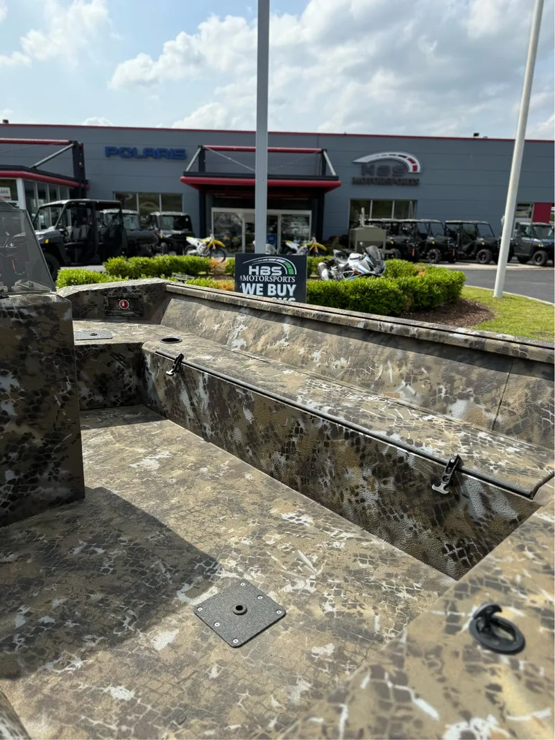 Slide: The Image of 2025 Excel 1751 Side Console River Warrior boat at dealership, camouflage design, sunny day. - 5