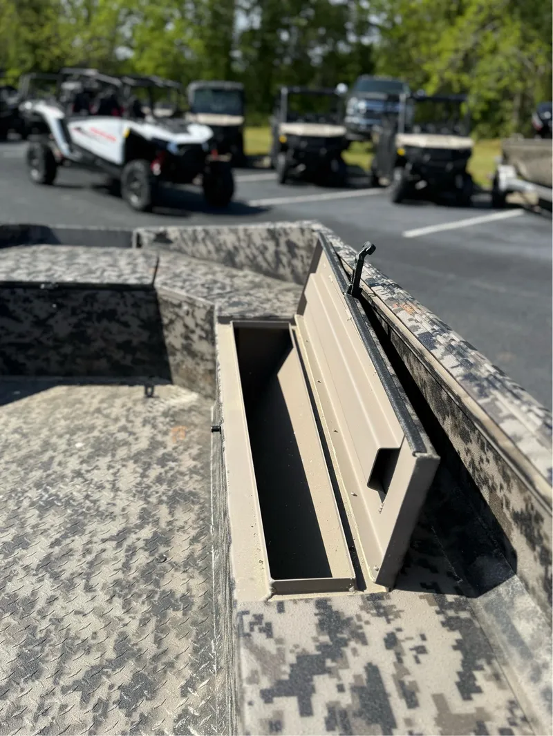 Slide: The Image of 2025 EDGE BOATS 653 DB with open storage compartment, off-road vehicles in background. - 13