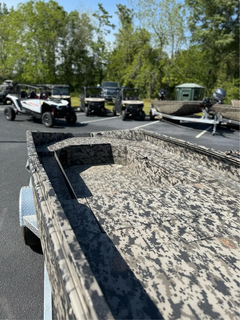 Slide: The Image of 2025 EDGE BOATS 653 DB with camouflage design, parked outdoors with off-road vehicles nearby. - 9