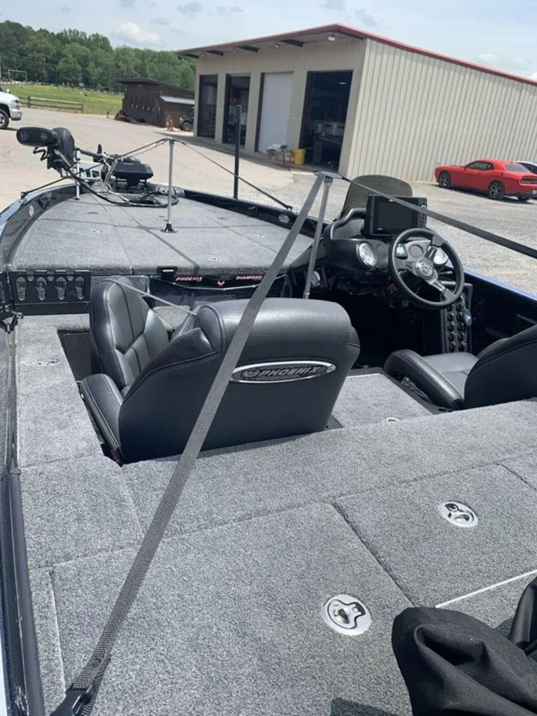 Slide: The Image of 2024 Phoenix Bass Boats 518 Pro interior with steering wheel and seating, parked near a garage. - 5