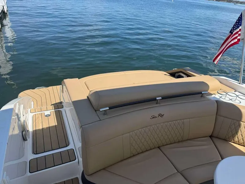 Slide: The Image of 2023 Sea Ray SLX 310 boat with tan seating and American flag on calm water. - 7