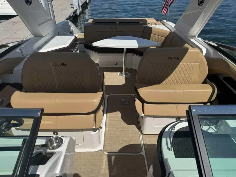 Slide: The Image of 2023 Sea Ray SLX 310 boat interior with tan seating and table, docked by water. - 8