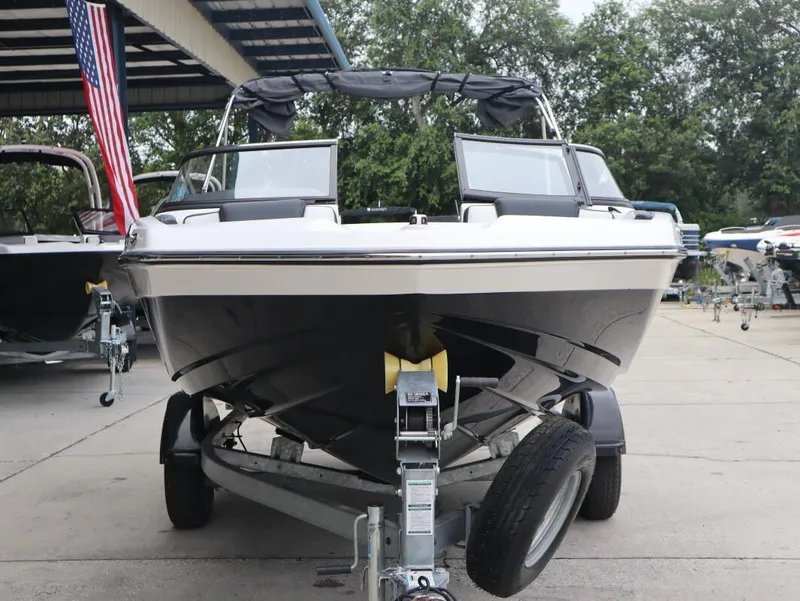 Slide: The Image of 2019 Yamaha Boats SX195 on trailer, parked outdoors with American flag nearby. - 7