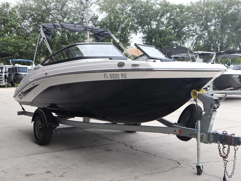 Slide: The Image of 2019 Yamaha Boats SX195 on trailer, parked outdoors with trees in background. - 8
