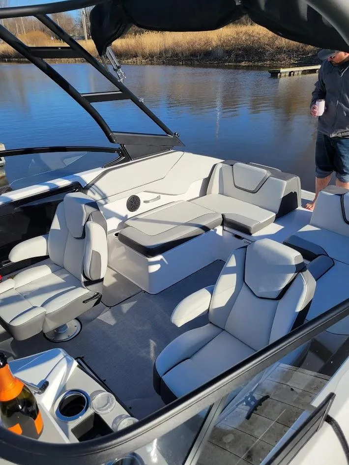Slide: The Image of 2023 Yamaha Boats AR250 interior with modern seating on a calm waterway. - 11