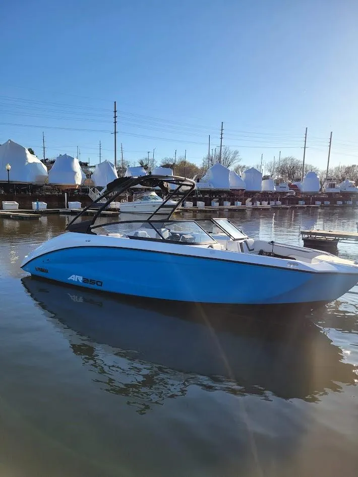 Slide: The Image of 2023 Yamaha Boats AR250 in calm marina waters under clear blue sky. - 13
