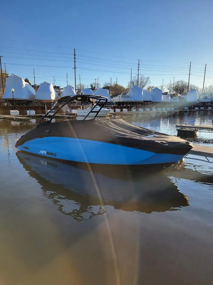 Slide: The Image of 2023 Yamaha Boats AR250 in a marina, reflecting on calm water under a clear sky. - 14
