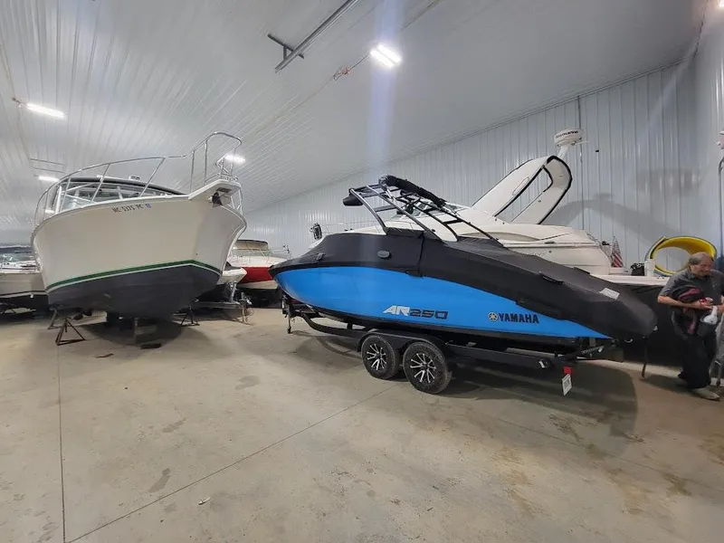 Slide: The Image of 2023 Yamaha AR250 boat in indoor storage, alongside other boats. - 15