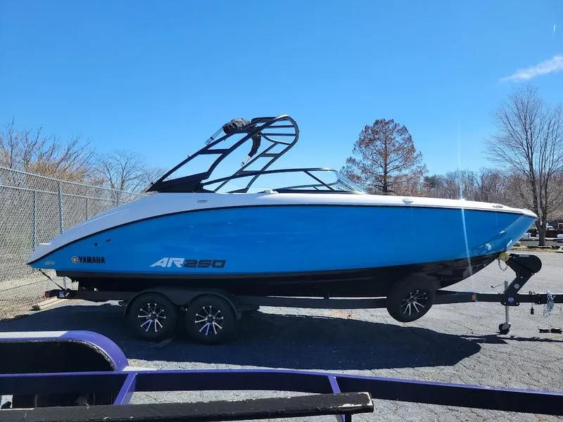 Slide: The Image of 2023 Yamaha AR250 boat on trailer, blue and white design, parked outdoors. - 3
