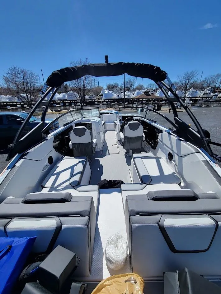 Slide: The Image of 2023 Yamaha Boats AR250 with spacious seating and sleek design, docked under clear blue sky. - 6
