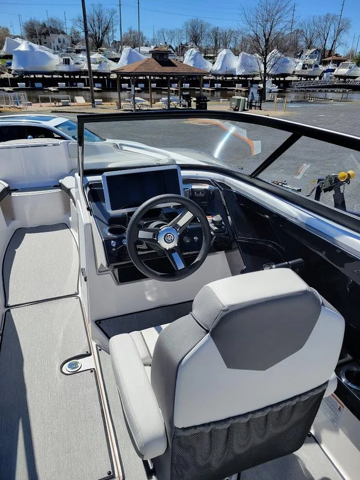Slide: The Image of 2023 Yamaha Boats AR250 cockpit with steering wheel and dashboard, docked at marina. - 8