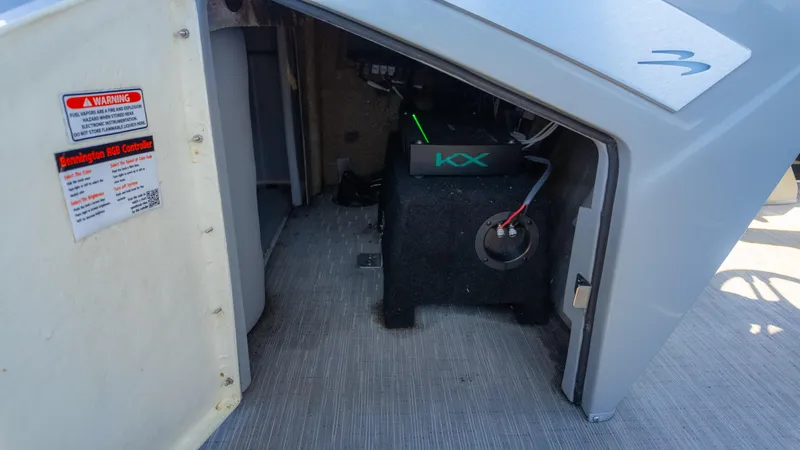Slide: The Image of 2022 Bennington 24 LXSBA boat storage compartment with KX audio equipment and warning label. - 27