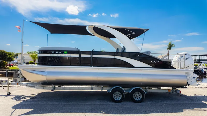 Slide: The Image of 2022 Bennington 24 LXSBA pontoon boat on trailer under blue sky. - 34
