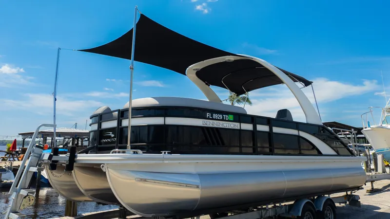 Slide: The Image of 2022 Bennington 24 LXSBA pontoon boat on trailer under blue sky. - 35