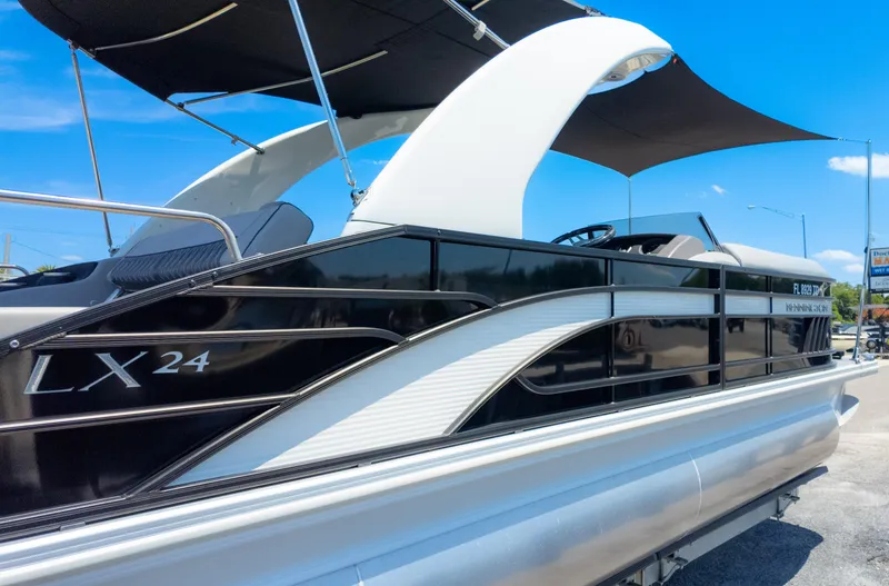Slide: The Image of 2022 Bennington 24 LXSBA pontoon boat with sleek black and white design under blue sky. - 5
