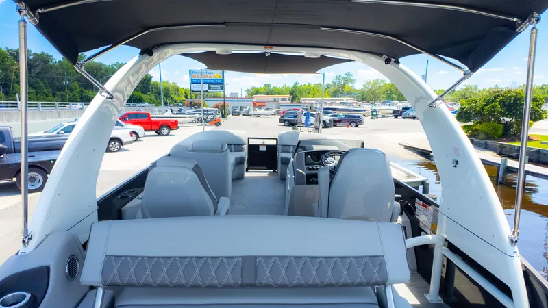 Slide: The Image of 2022 Bennington 24 LXSBA pontoon boat interior with seating and canopy, docked at marina. - 9