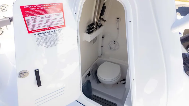 Slide: The Image of 2025 Tidewater 256CC boat interior with compact marine toilet and safety instructions. - 23