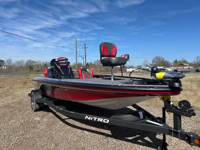 Slide: The Image of 2025 Nitro Z19 boat on trailer, red and black design, parked outdoors under blue sky. - 18