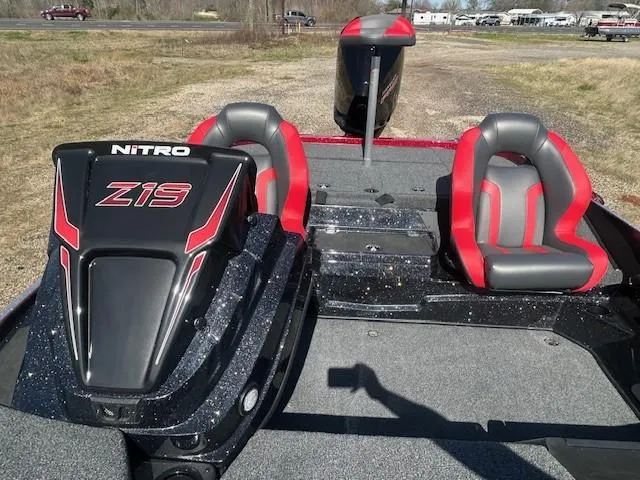 Slide: The Image of 2025 Nitro Z19 boat interior with red and gray seats, parked on grass. - 2