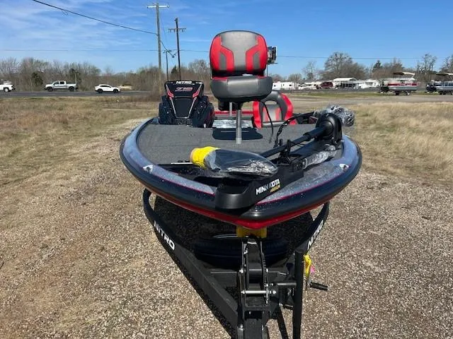 Slide: The Image of 2025 Nitro Z19 fishing boat with red seats and trolling motor, parked on gravel. - 5