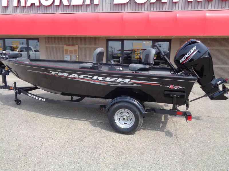 Slide: The Image of 2025 Tracker Super Guide V-16 T boat with Mercury engine on display outside dealership. - 2