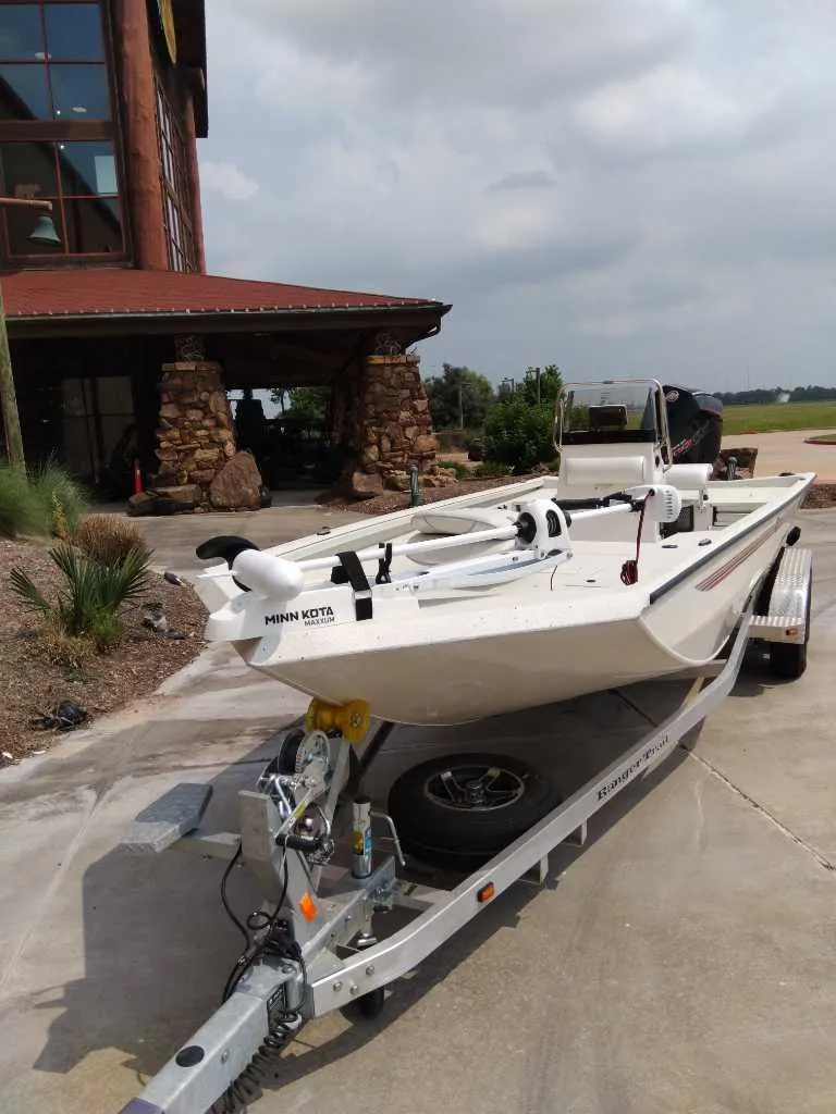 Slide: The Image of 2025 Ranger RB210 boat on trailer outside rustic building. - 1