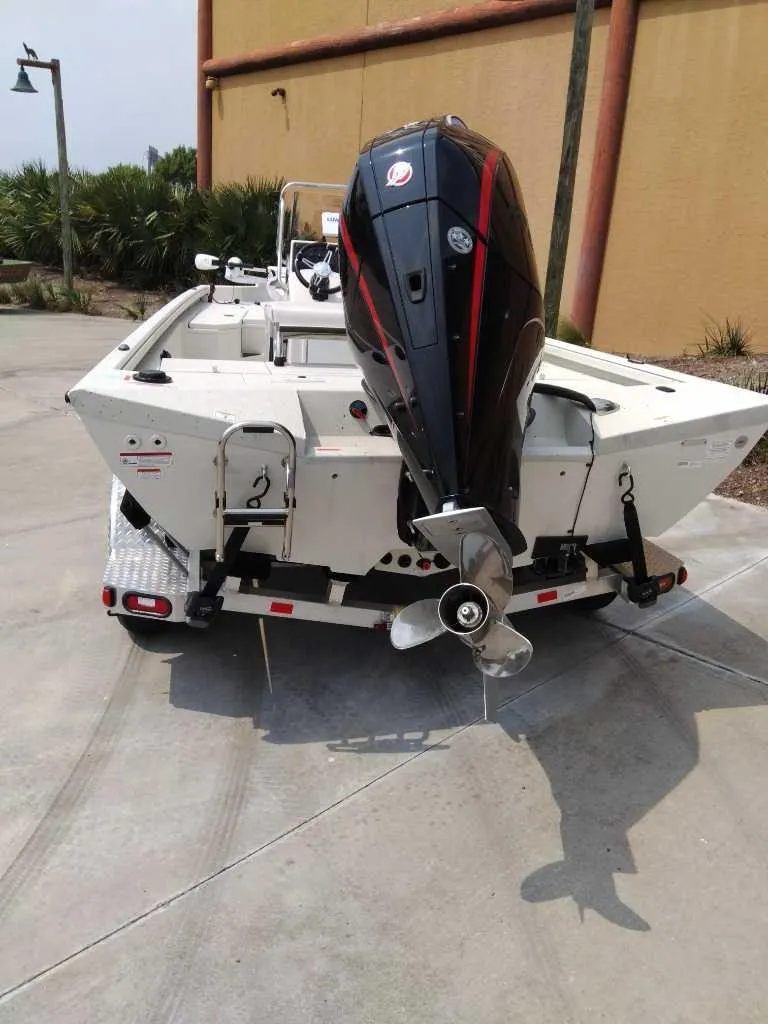 Slide: The Image of 2025 Ranger RB210 boat with outboard motor, parked on concrete near a building. - 4