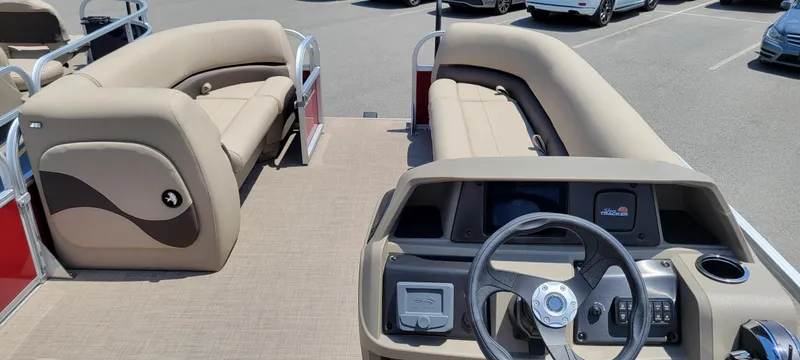 Slide: The Image of 2025 Sun Tracker Party Barge 18 DLX interior with beige seating and steering console. - 4
